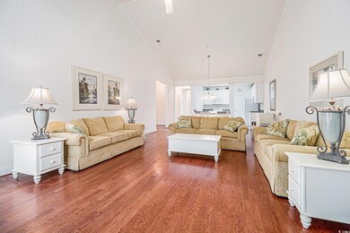 Living area with high vaulted ceiling, wood finished floors, a chandelier, and baseboards