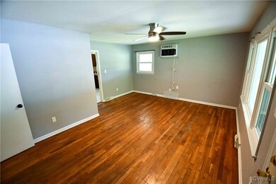Empty room featuring an AC wall unit, ceiling fan,