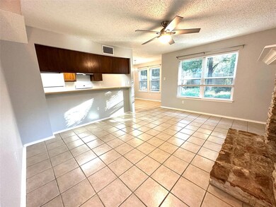 Unfurnished living room with light tile patterned floors, ceiling fan, and a textured ceiling