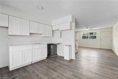 Kitchen with white cabinetry, white fridge, ceiling fan, dark wood-type flooring, and a textured ceiling