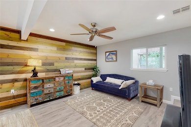 Living area with ceiling fan, wood accent wall, re