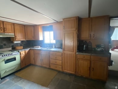Kitchen featuring electric range, tasteful backsplash, under cabinet range hood, and brown cabinetry