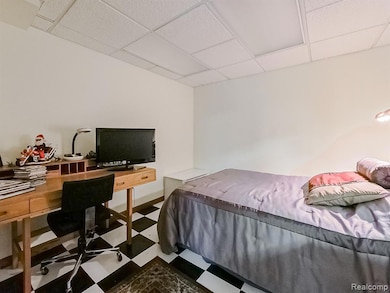 Bedroom featuring an office area, a paneled ceiling, and dark floors