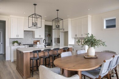 Kitchen featuring an island with sink, white cabinets, light wood finished floors, decorative backsplash, and recessed lighting