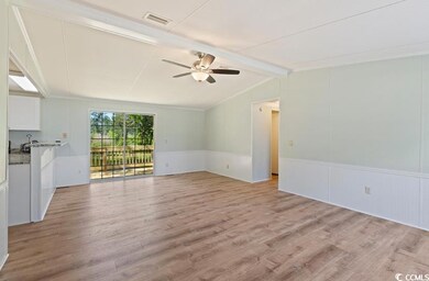 Unfurnished living room featuring a ceiling fan, light wood-type flooring, wainscoting, and a decorative wall