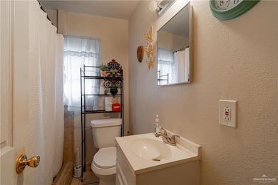 Bathroom featuring a textured wall, vanity, and toilet