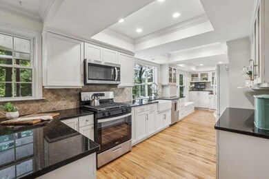 Spacious Kitchen With Granite Counters, Garden Window Above The Farmhouse Sink, & A Wall Of Windows