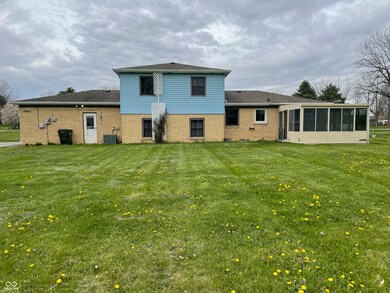 rear view of property with central air condition unit, a sunroom, a yard, and brick siding