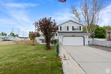 Traditional-style house featuring a garage, a front lawn, fence, and driveway