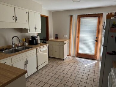 Kitchen with white appliances, light tile patterned flooring, white cabinets, and light countertops