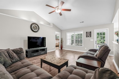 Living room with a ceiling fan, wood finished floors, and high vaulted ceiling