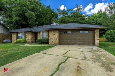 Single story home with brick siding, driveway, a garage, and roof with shingles