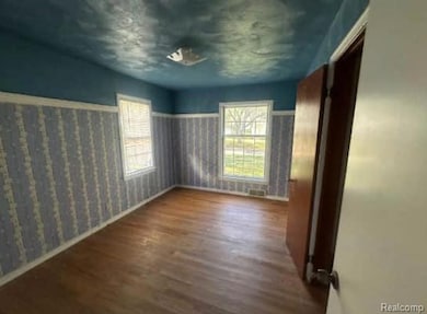 Unfurnished bedroom with dark wood-type flooring and multiple windows