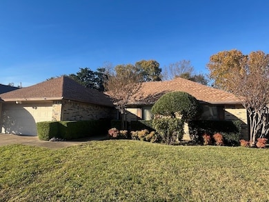 View of front of property featuring a front yard, a garage, concrete driveway, and brick siding