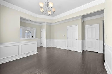 Empty room with visible vents, wainscoting, orname