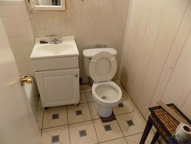 Bathroom with toilet, wood walls, vanity, and tile
