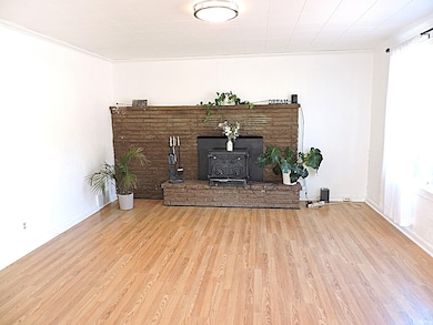 Unfurnished living room featuring a wood stove, light wood-type flooring