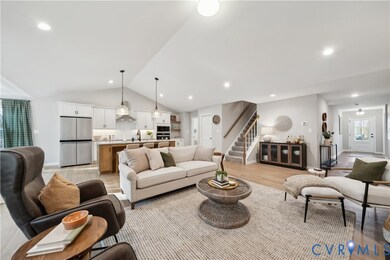 Living area with vaulted ceiling, stairs, light wood-style flooring, and recessed lighting