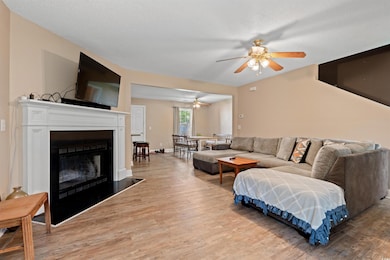 Living room with ceiling fan, light wood-type flooring, and a fireplace