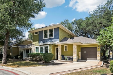 View of front facade with stone siding, concrete driveway, roof with shingles, and a garage