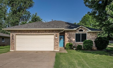 View of front facade featuring driveway, a front yard, a shingled roof, an attached garage, and brick siding