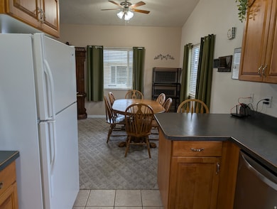Kitchen featuring brown cabinets, freestanding refrigerator, dark countertops, and stainless steel dishwasher