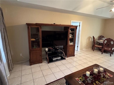 Living room with light tile patterned flooring, ceiling fan, and baseboards