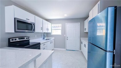 Kitchen featuring stainless steel appliances, a sink, white cabinetry, and light stone countertops