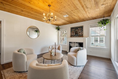 Living area featuring plenty of natural light, a fireplace, wood finished floors, a chandelier, and wooden ceiling