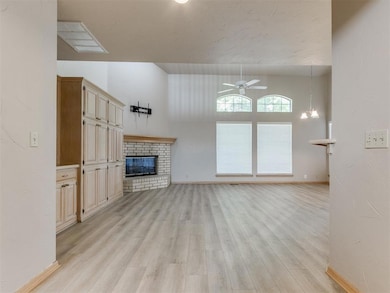 Unfurnished living room with ceiling fan, light wood finished floors, a brick fireplace, and baseboards