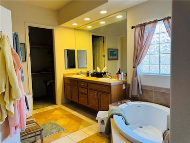 Bathroom with double vanity, light tile patterned flooring, a bath, recessed lighting, and a walk in closet