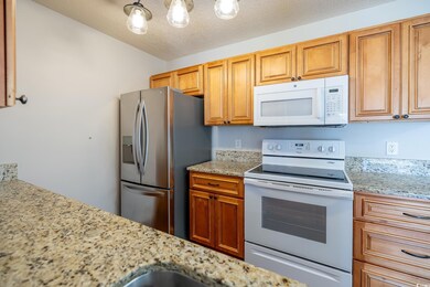 Kitchen with light stone countertops, white applia