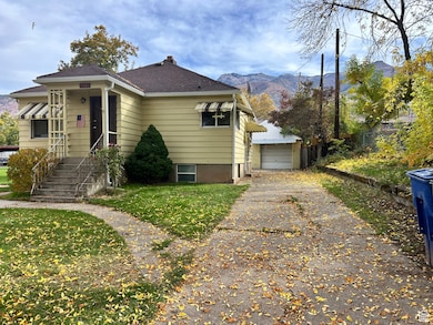 View of front of home with a mountain view, an outbuilding, roof with shingles, a detached garage, and a chimney
