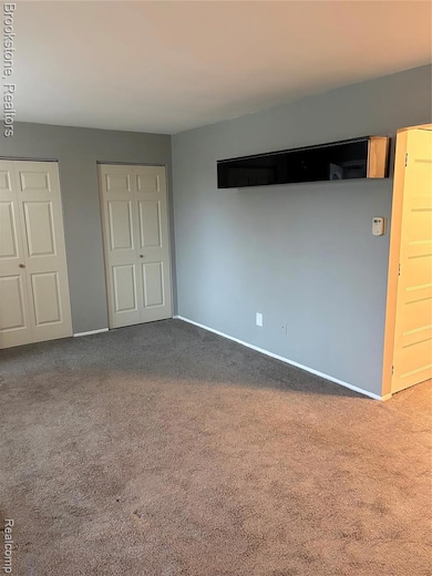 Unfurnished bedroom with two closets and carpet