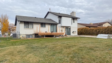 Rear view of property featuring a shingled roof, a chimney, and a deck