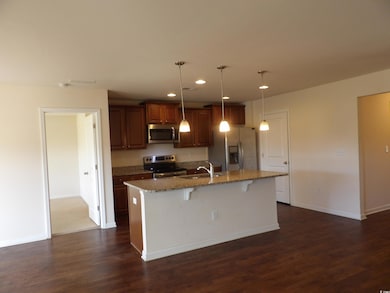 Kitchen featuring stainless steel appliances, a center island with sink, a breakfast bar, dark wood-style floors, and recessed lighting