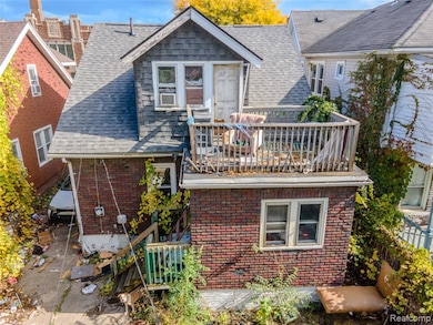 Rear view of property with roof with shingles, a wooden deck, and brick siding
