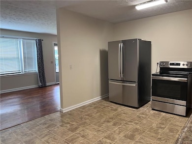 Kitchen featuring appliances with stainless steel finishes, a textured ceiling, and baseboards