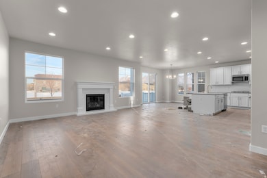 Unfurnished living room featuring recessed lighting, a glass covered fireplace, light wood-type flooring, a chandelier, and healthy amount of natural light