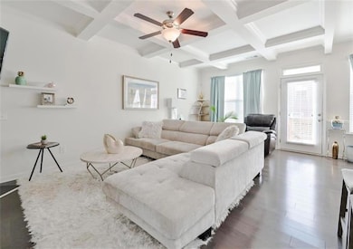 Living area featuring coffered ceiling, beamed ceiling, ceiling fan, and wood finished floors