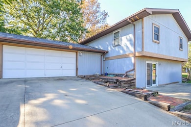 View of front of property featuring concrete driveway, roof with shingles, and a garage
