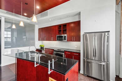 Kitchen featuring stainless steel appliances, recessed lighting, dark brown cabinets, backsplash, and a center island with sink