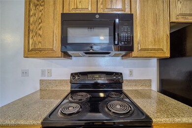 Kitchen featuring black appliances, light stone counters, and brown cabinets