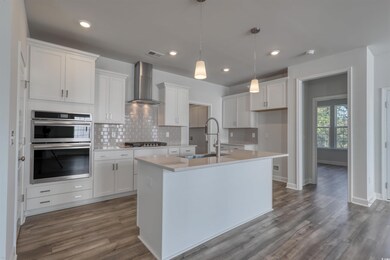 Kitchen featuring white cabinetry, sink, wall chim