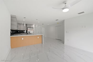 Kitchen with gray cabinetry, a peninsula, open shelves, decorative backsplash, and pendant lighting