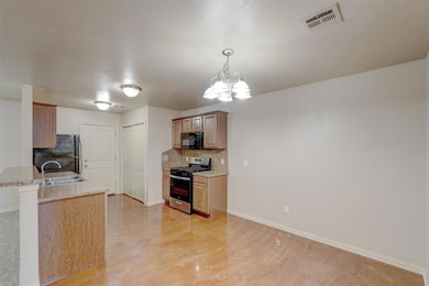 Kitchen featuring black appliances, decorative backsplash, a chandelier, light stone countertops, and pendant lighting