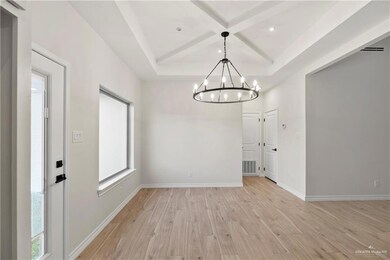 Unfurnished dining area featuring light hardwood / wood-style floors, an inviting chandelier, and a raised ceiling