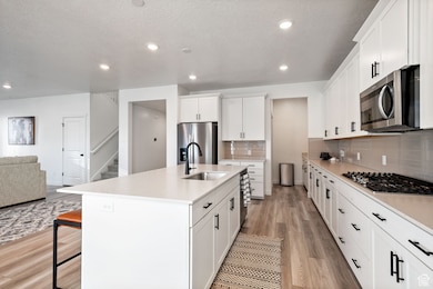 Kitchen with light wood-style flooring, open floor plan, stainless steel appliances, a breakfast bar, and light countertops