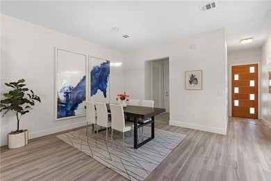 Dining room featuring baseboards, light wood finished floors, and visible vents