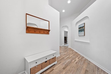 Hallway featuring wood finished floors, arched walkways, ornamental molding, and recessed lighting